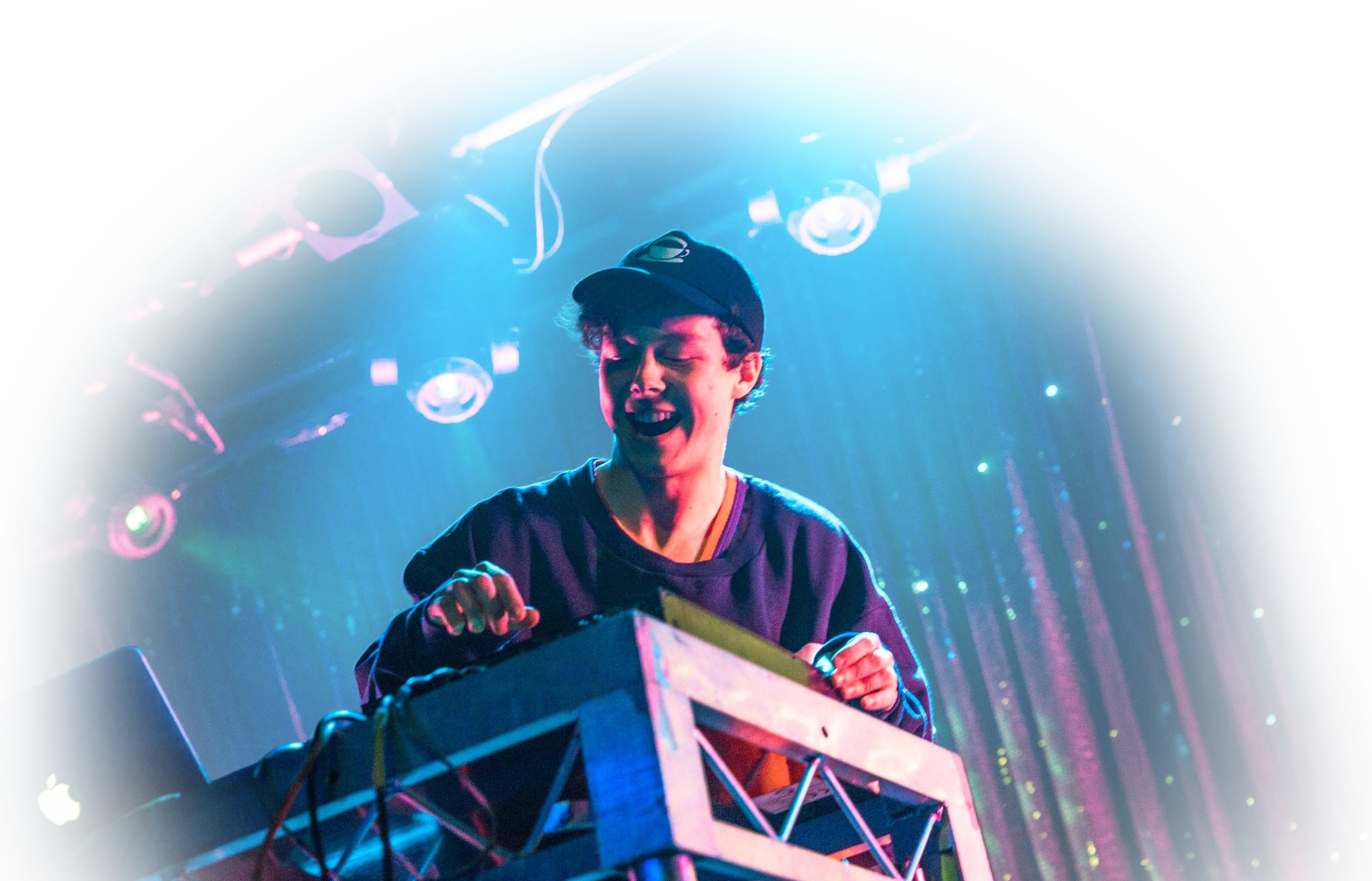 Jonny Woolley operating a sound desk under cyan and magenta stage lighting